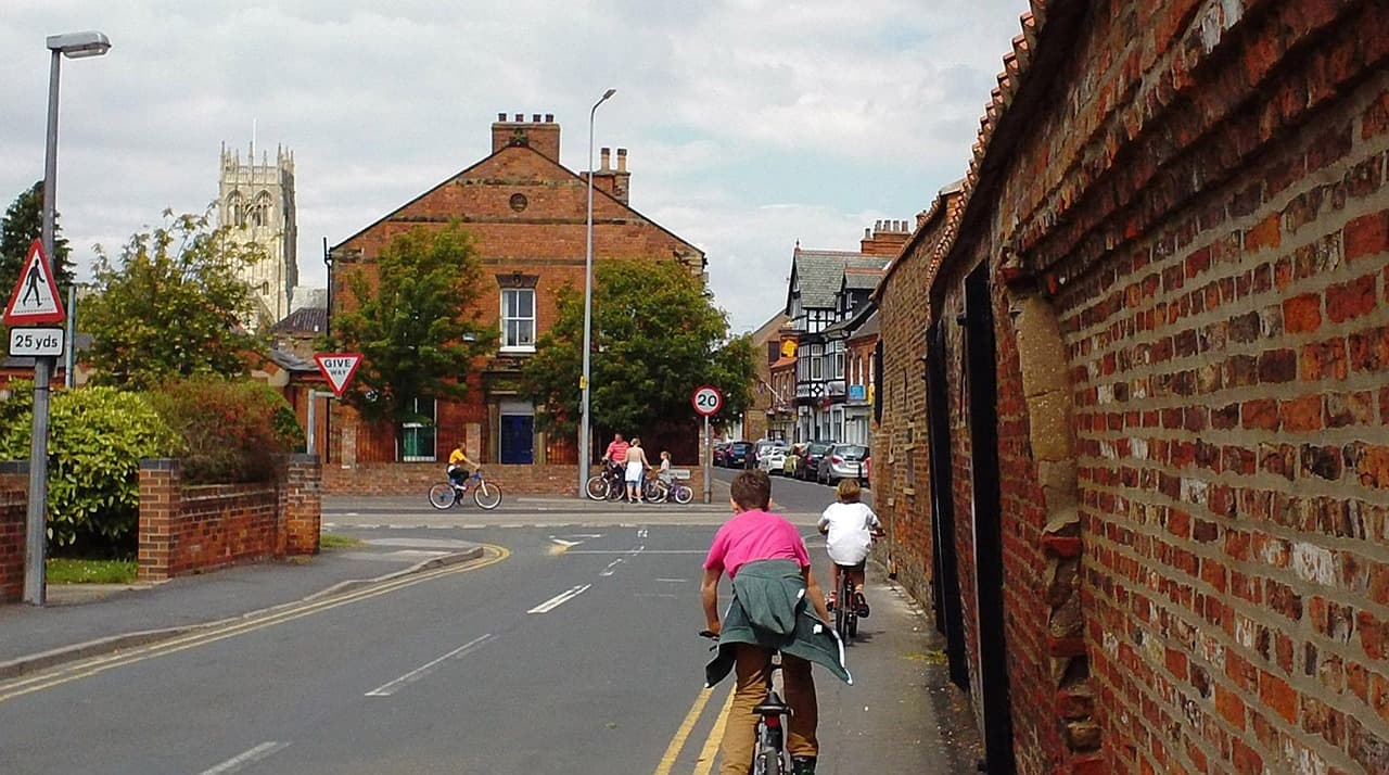 Two cyclists approaching a give way junction on a British town road