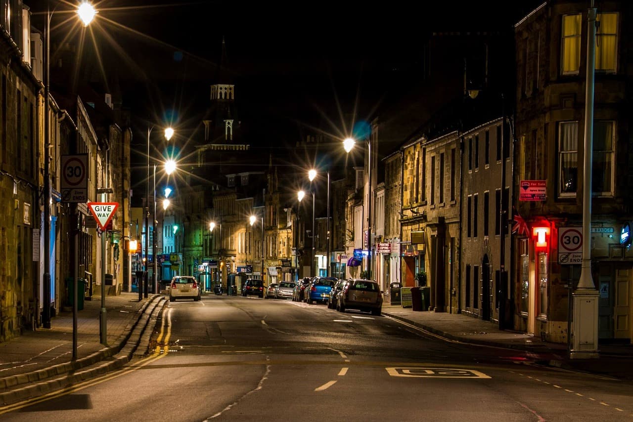 A quiet British high street at night, with a give way sign and 30 limit